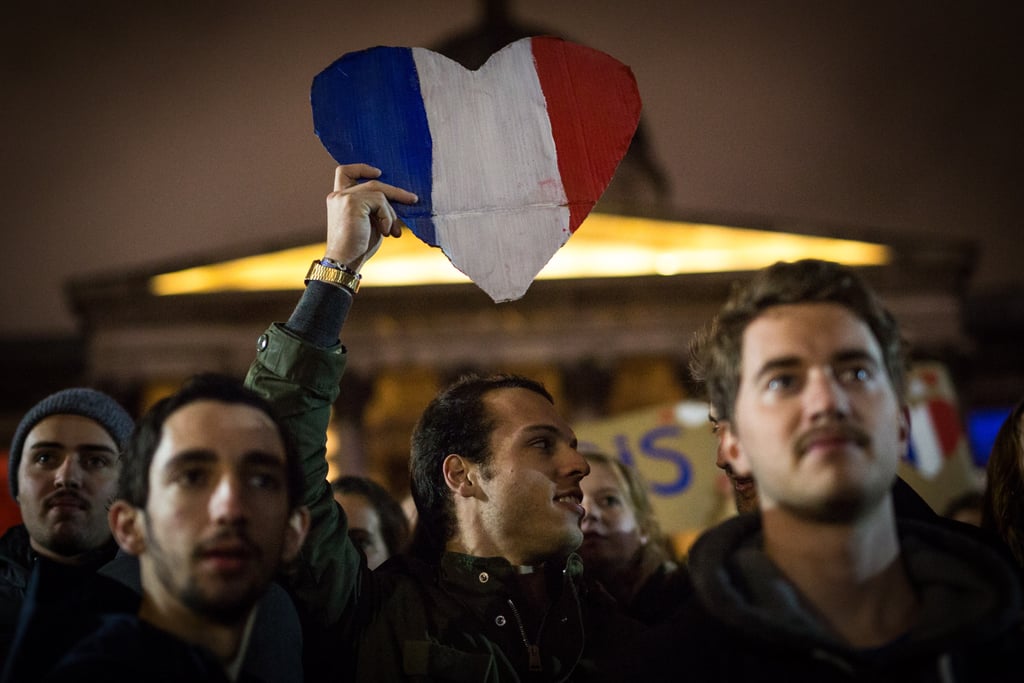 A man waved a French flag in the shape of a heart during a vigil in London.