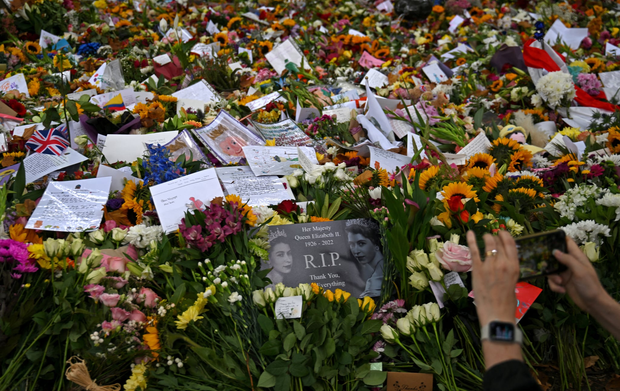 Members of the public look at flowers and tributes left in Green Park in London on September 13, 2022, following the death of Queen Elizabeth II on September 8. - Queen Elizabeth II's coffin will on Tuesday be flown by the Royal Air Force from Edinburgh to London, accompanied by the queen's only daughter Anne, the Princess Royal, and driven to Buckingham Palace, to rest in the Bow Room. (Photo by CARL DE SOUZA / AFP) (Photo by CARL DE SOUZA/AFP via Getty Images)