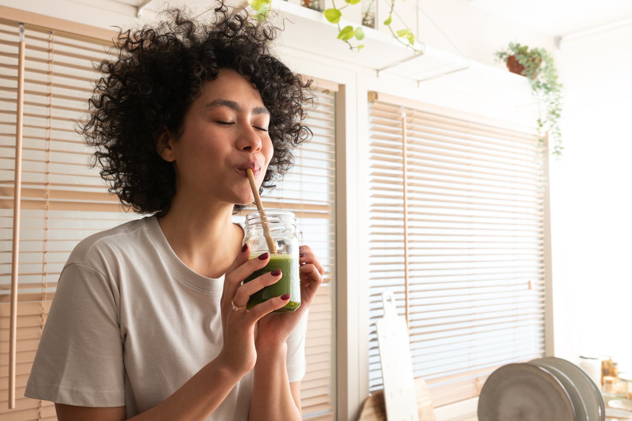 Woman drinking green smoothie with straw.