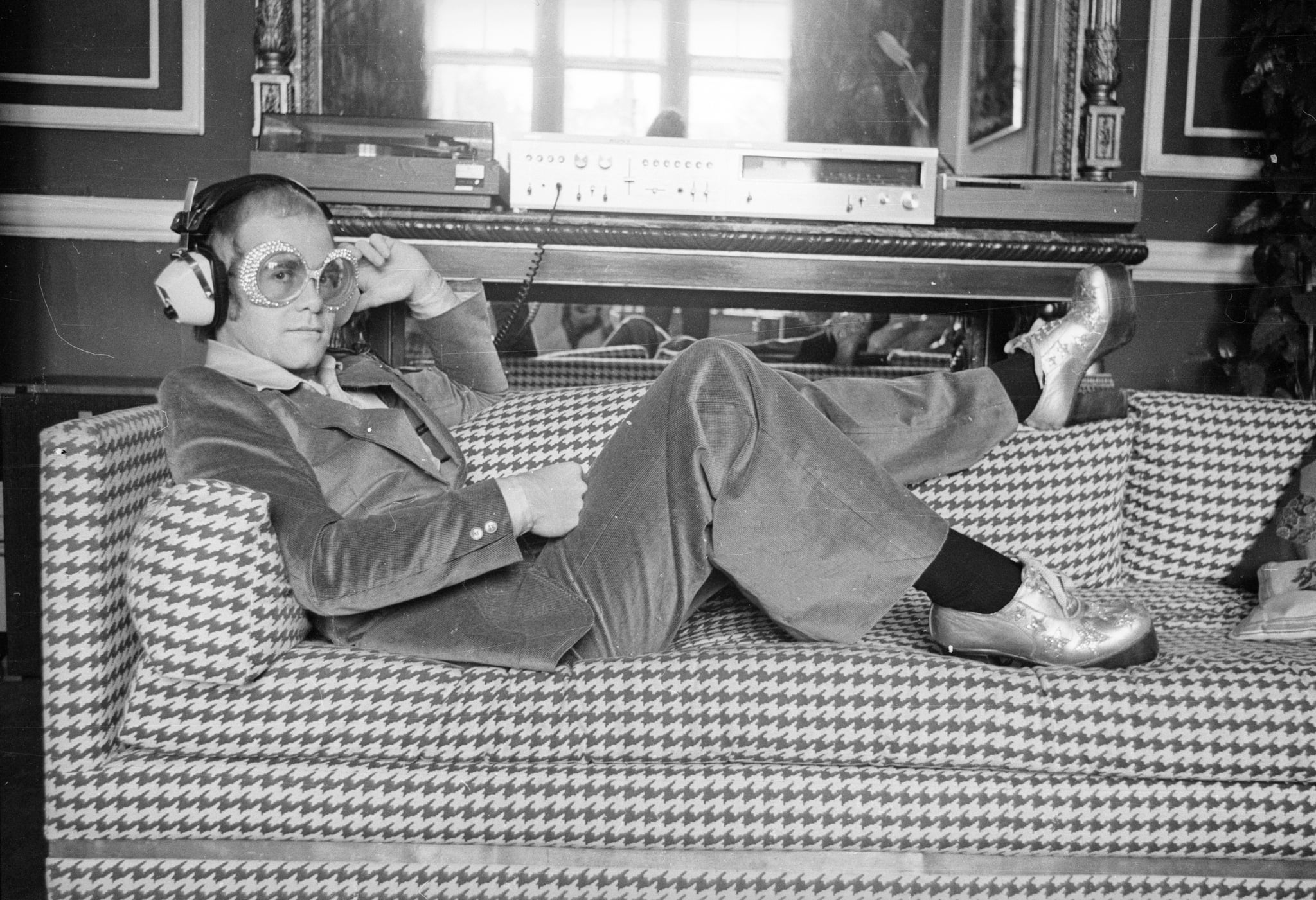 12th September 1974:  English pop star Elton John relaxes on a sofa and listens to some music.  (Photo by D. Morrison/Express/Getty Images)