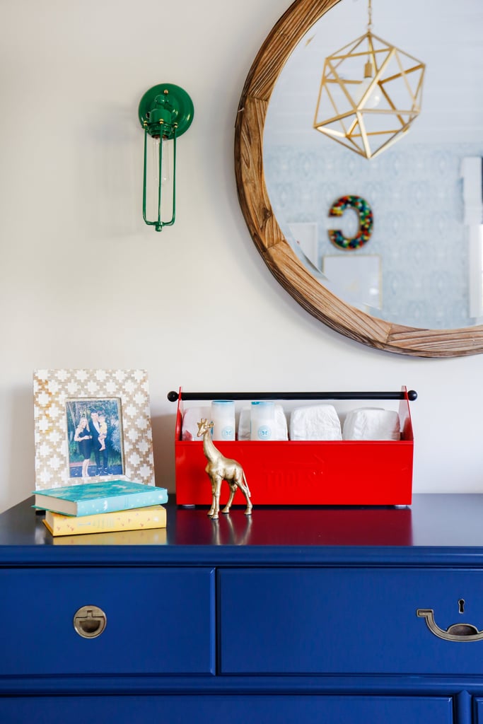 A rustic mirror and vintage light fixtures complete the look, while diapering supplies are creatively displayed in a toolbox.