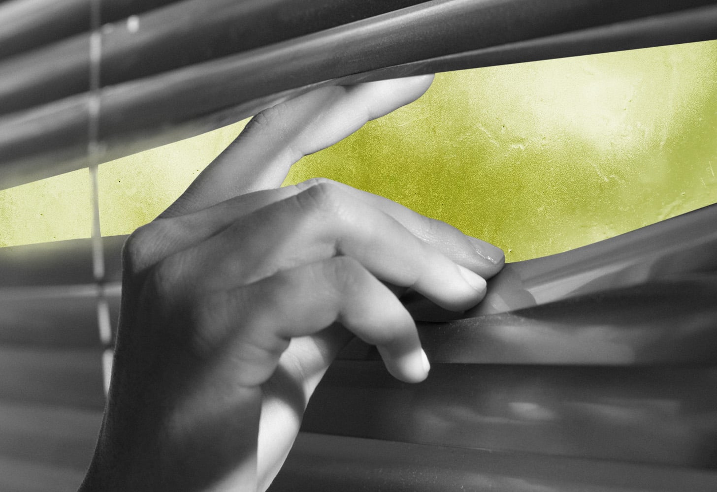 Woman peeping out of window blinds.