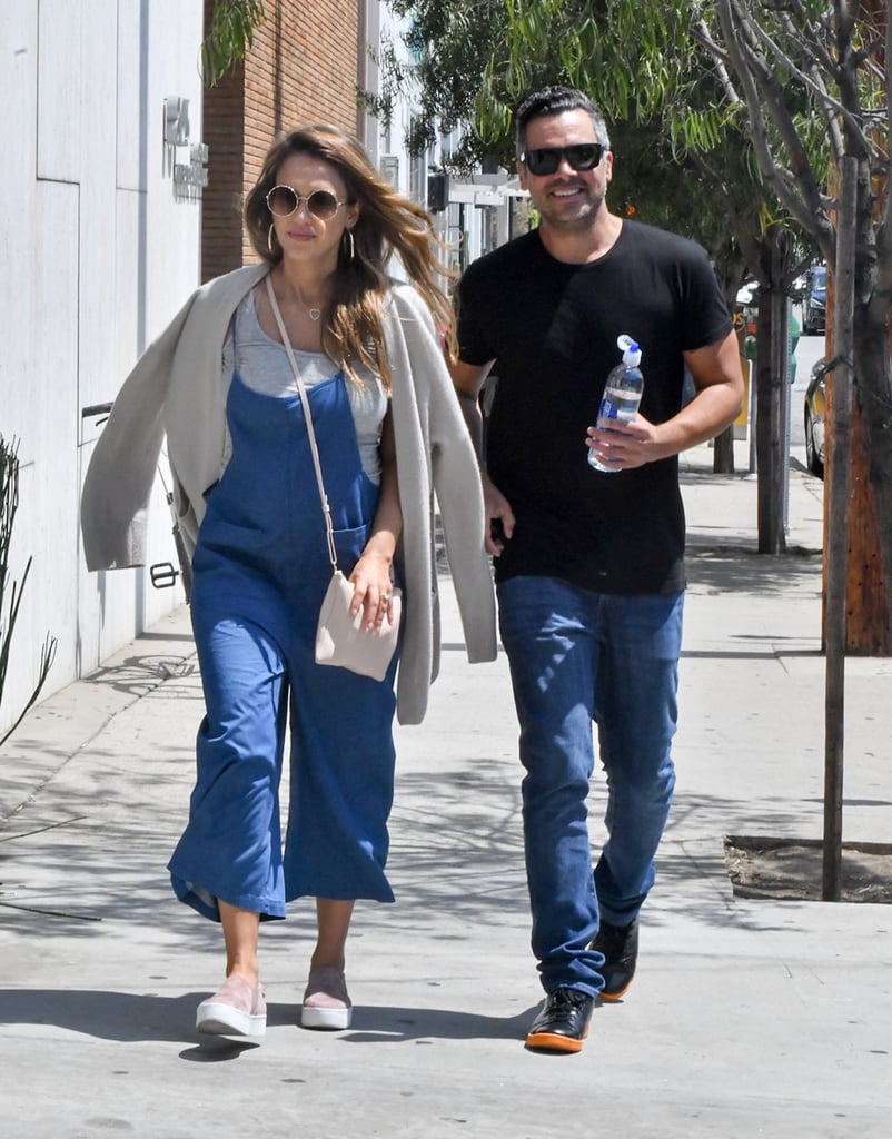 Jessica goes for a stroll with her husband on a sunny LA day. She wears a casual denim jumpsuit with a neutral tank, cardigan, and sneakers.