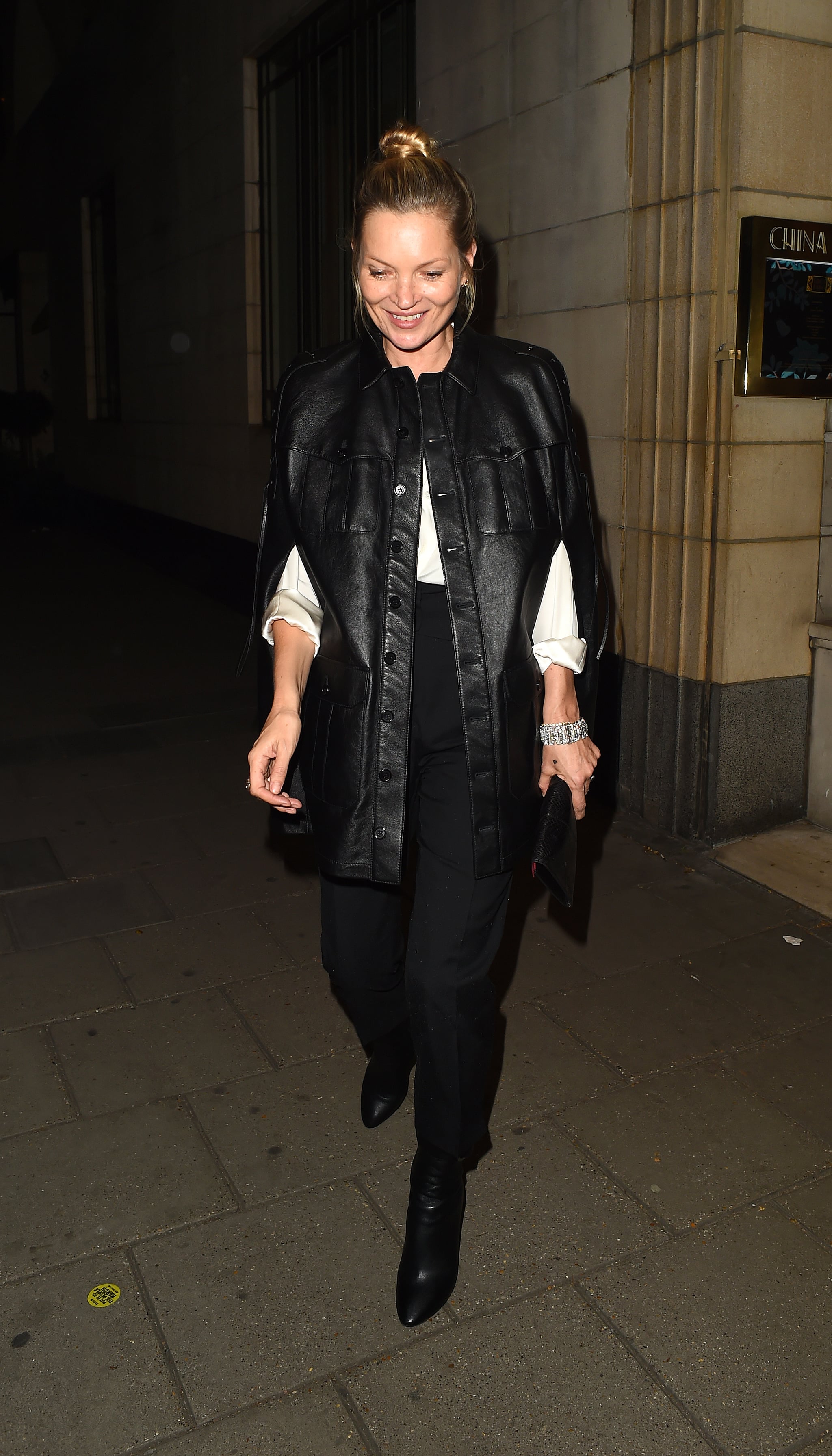 Kate Moss pairs a monochromatic look with a a very chic black leather cape coat while leaving Meg Mathews birthday party at The Dorchester.