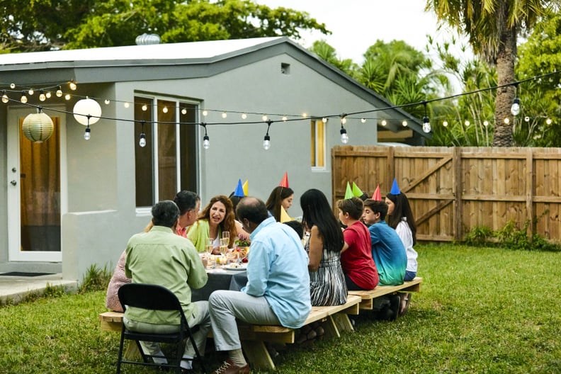 Multi-generation family enjoying birthday party. Family is celebrating at back yard. They are sitting at dining table.