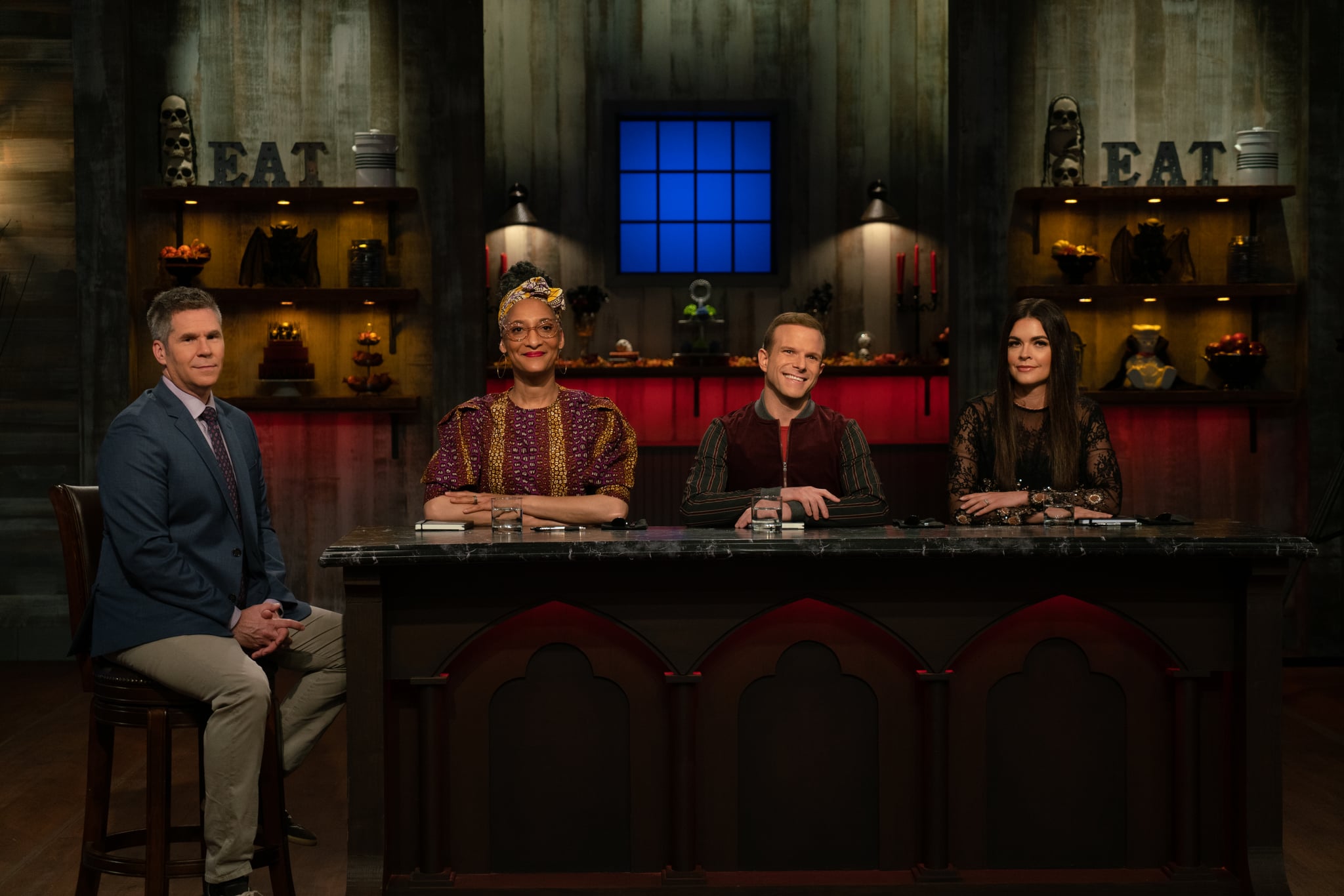 Posed shot of Host John Henson with Judges Carla Hall, Zac Young, and Katie Lee as seen on Halloween Baking Championship Season 5 Episode 5.
