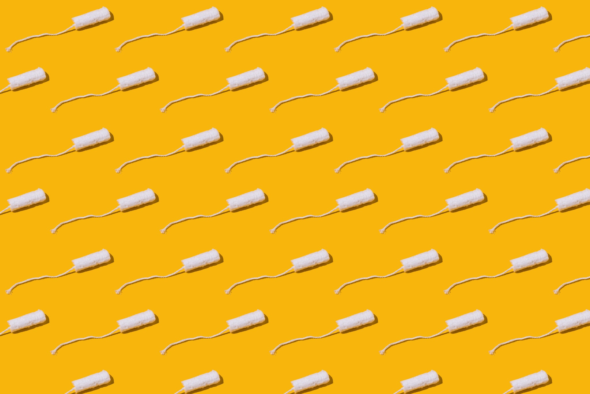 Cellulose white tampon pattern with twine on yellow background. Concept of menstruation, ovulation, reproduction, pain and personal hygiene.