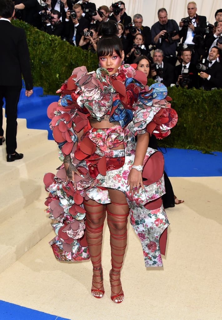 Rihanna pulled out all the stops with her 2017 Met Gala look. Sticking to the theme of the night by honoring Rei Kawakubo, Rihanna donned an intricate floral dress from Comme des Garçons's Fall 2016 collection. Rihanna's stunning look embodied the fantasy artwork Kawakubo is known for including in her design pieces. Keep reading to see the "Diamonds" singer full Met Gaga regalia, which includes killer gladiator heels, whimsical eye and cheek makeup, and a fierce top knot bun.