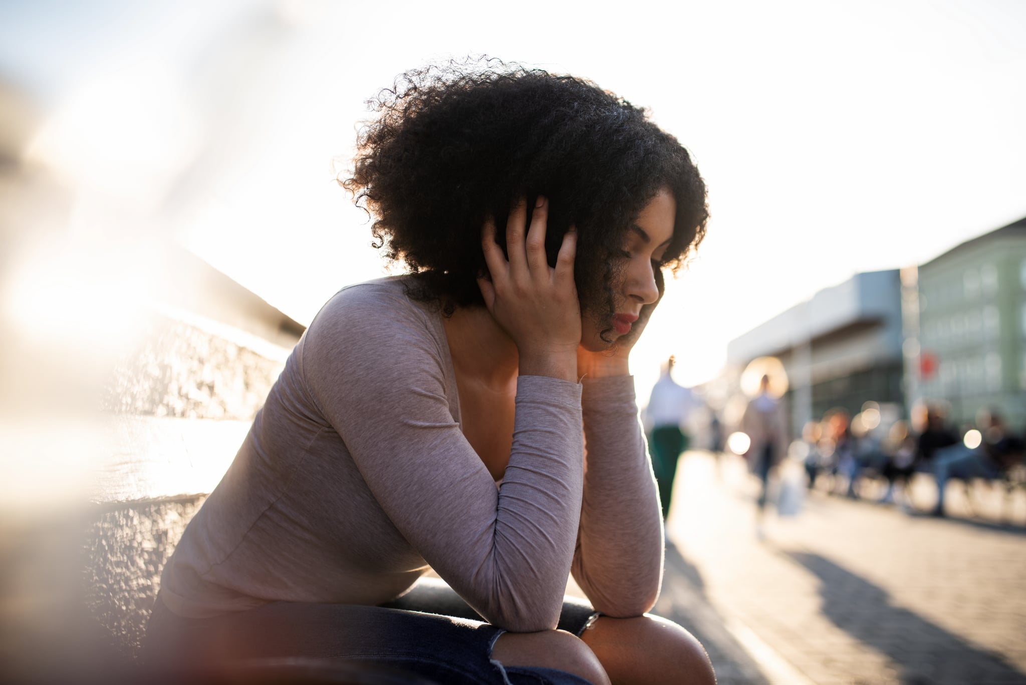 Teenage sad woman sitting on city street