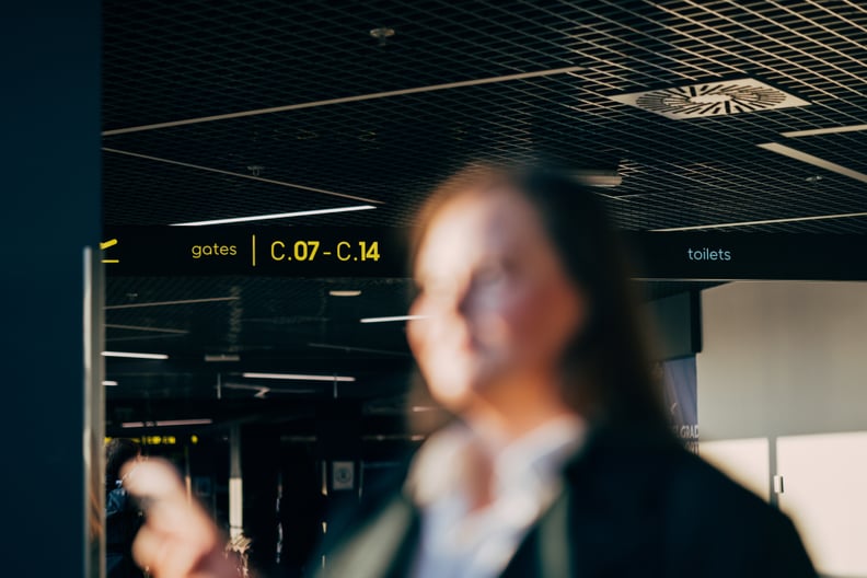 A blurred image of a plus-size traveler with airport terminals and gate signs in the background.