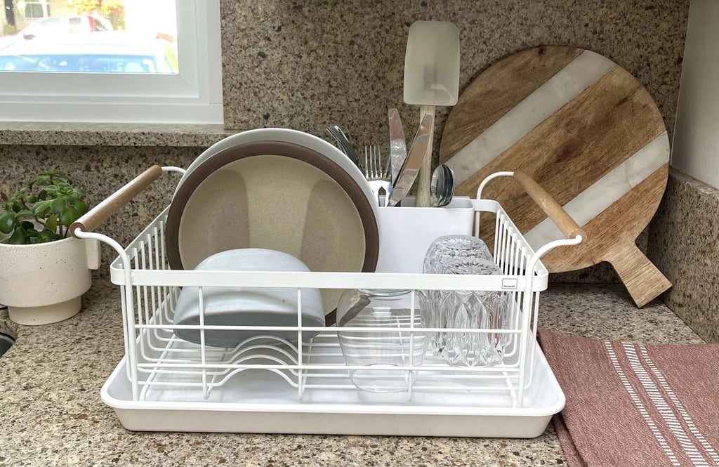 Yamazaki Home Dish Rack ($98)
For an aesthetically-pleasing and compact dish rack, it doesn't get better than this option from Yamazaki Home. Instead of having a traditional draining tray, this one holds water in and doesn't need to be placed next to the sink. It's a lifesaver for kitchens with limited counter space, since you can easily tuck it into a corner during food prep. Our editor tested it in her own kitchen and insists it's worth the splurge. Check out more photos and details in our Yamazaki Home Dish Rack review.
Editor Quote: "Inspired by Scandinavian design and 'small space living' in Japan, this dish rack is an aesthetic dream. Its white, coated-steel frame and lacquer-coated wooden handles are the perfect balance of minimalism and warmth. I never thought I'd say this about a dish rack, but it looks beautiful on my kitchen counter." — Angela Elias, former contributing shopping editor