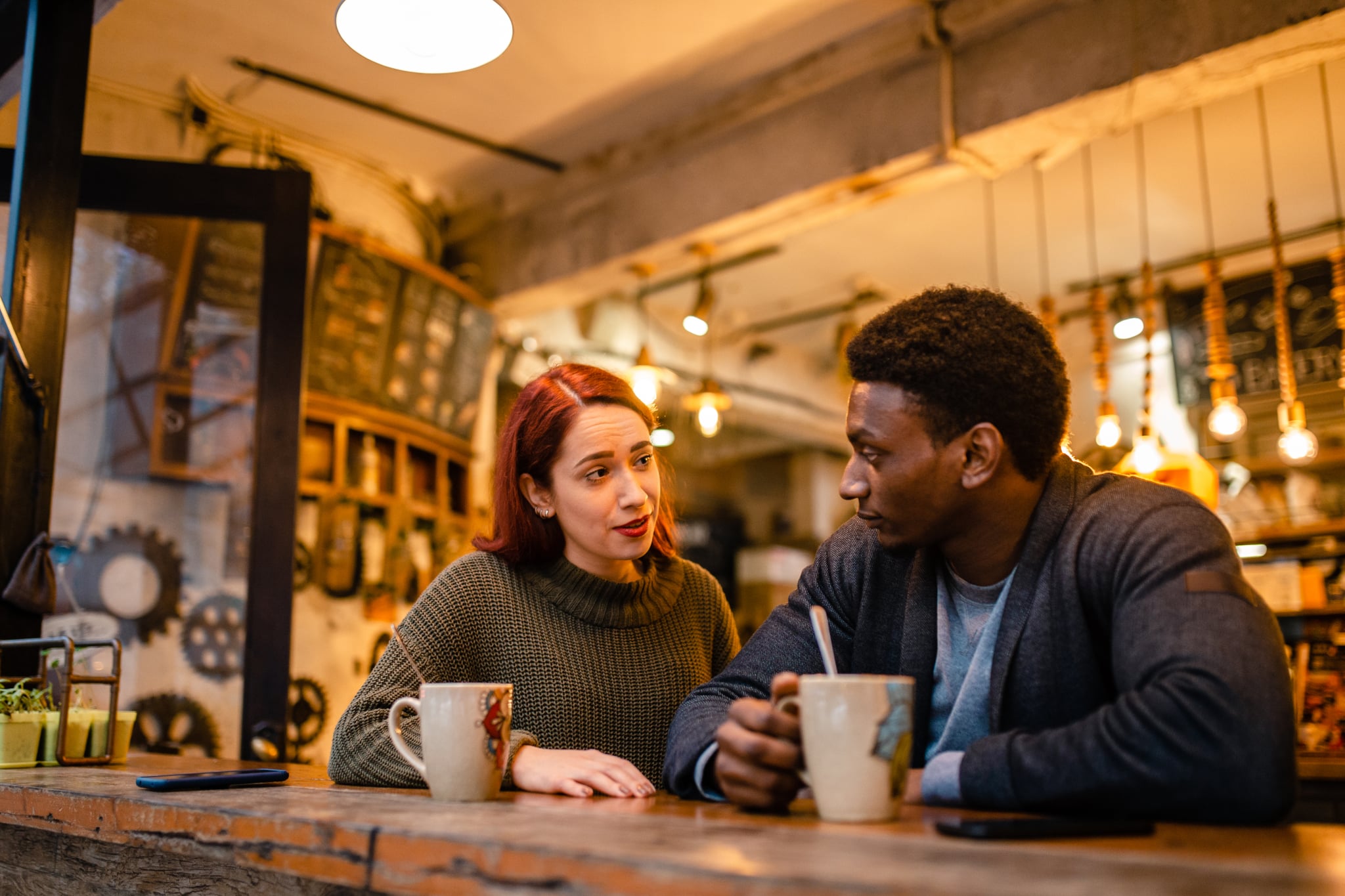 Angry jealous young woman have a fight with her African-american boyfriend at the modern cafeteria