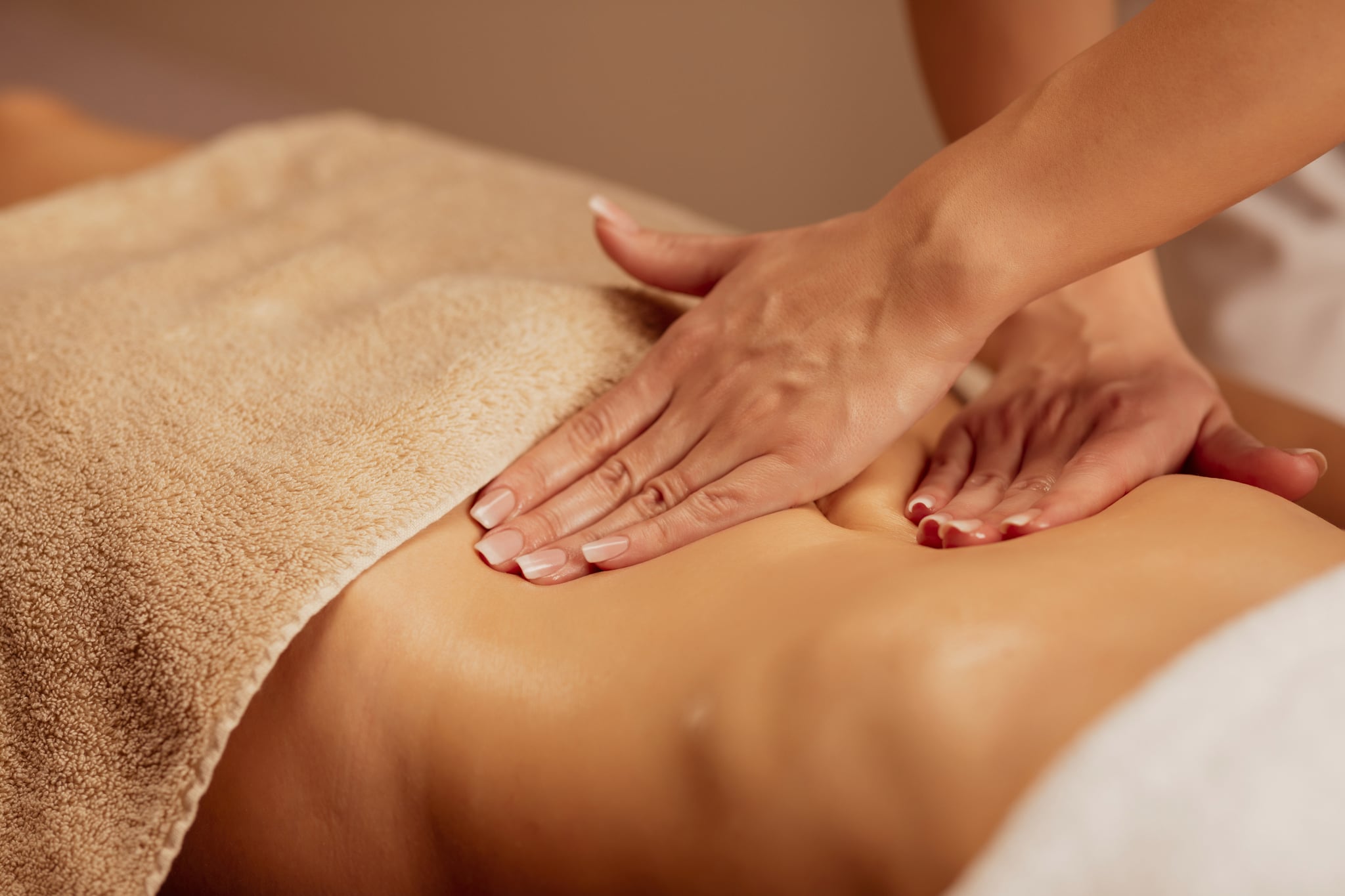 Belly massage. Anti cellulite massage.  Massage Therapist doing healing massage with rolling pin or battledore . Woman enjoying in relaxing massaging at health spa treatment.