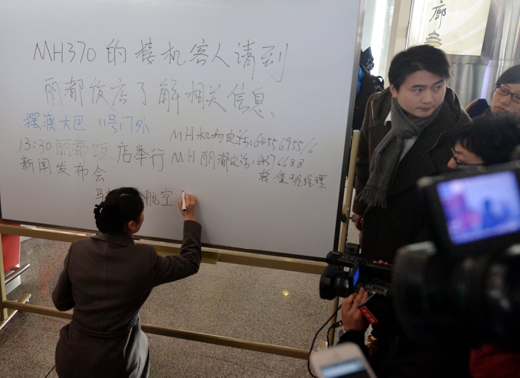 A woman handwrote a message to passengers' families at Beijing Capital International Airport, instructing them to await further information on the flight at a nearby hotel.