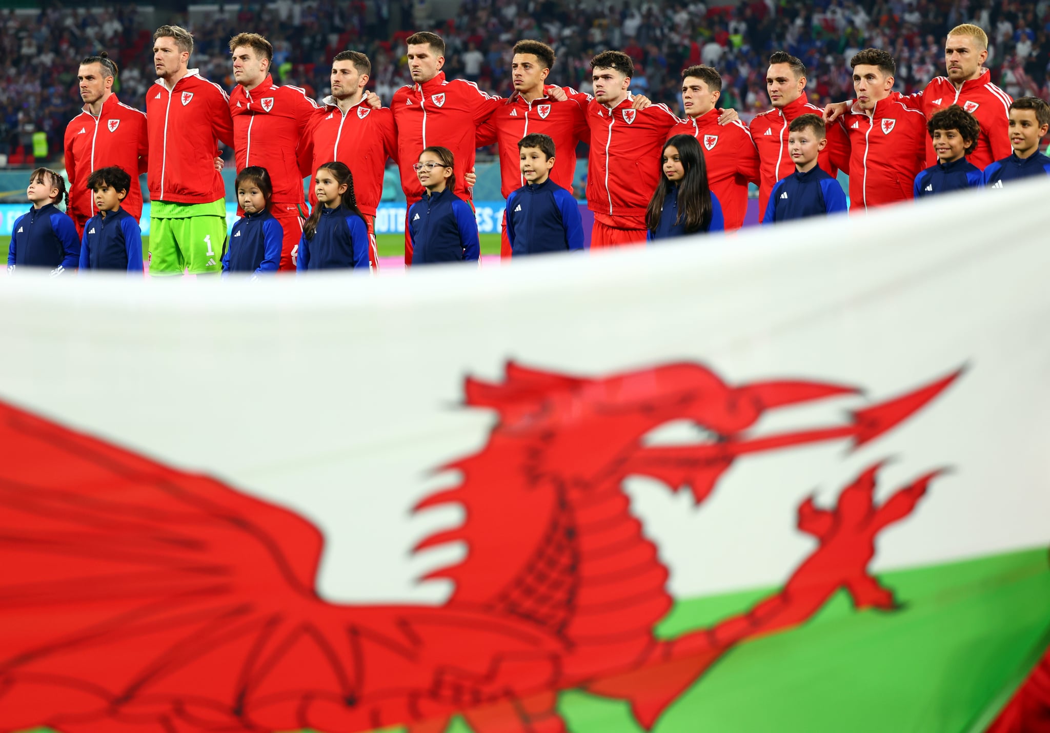 21 November 2022, Qatar, Ar-Rayyan: Soccer: World Cup, USA - Wales, Preliminary Round, Group B, Matchday 1, Ahmed bin Ali Stadium, Wales players stand with escort children behind the Welsh flag before the start of the match. Photo: Tom Weller/dpa (Photo by Tom Weller/picture alliance via Getty Images)