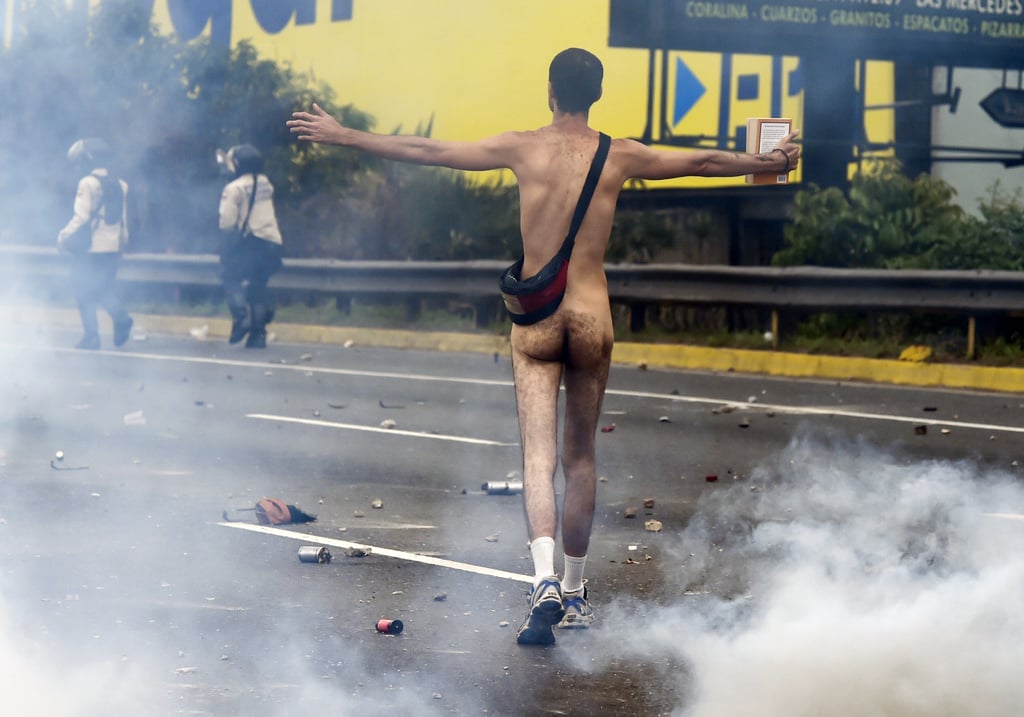 A naked protester faces off with riot police.