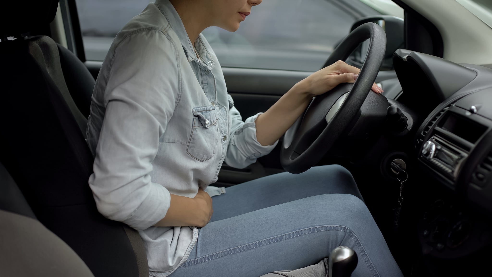Attractive lady driving car feeling strong premenstrual pain, hormone imbalance