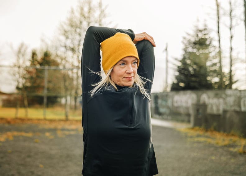 Woman stretching arms in the city park before a run. 