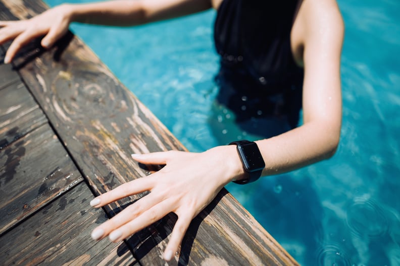 Close up of young female swimmer with smartwatch getting out from swimming pool