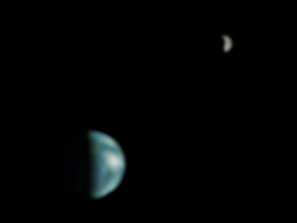 Although not totally clear, this is the first picture of Earth ever taken from another planet that shows it as a planetary disk. Here, we see the Earth and the moon from Mars, captured by the NASA Mars Global Surveyor on May 8, 2003. 
Source: NASA/JPL/Malin Space Science Systems