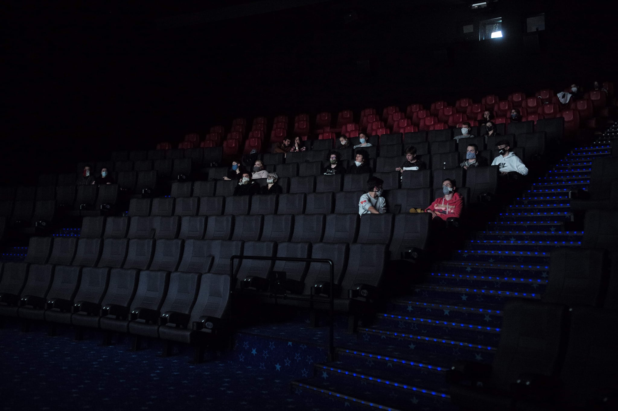 People wearing face masks watch a film in a cinema on May 11, 2020 in Prague as shopping malls, restaurant outdoor seating, hairdressers and cinemas may reopen after a two-month pause in Czech Republic as lockdown measure eases. (Photo by Michal Cizek / AFP) (Photo by MICHAL CIZEK/AFP via Getty Images)
