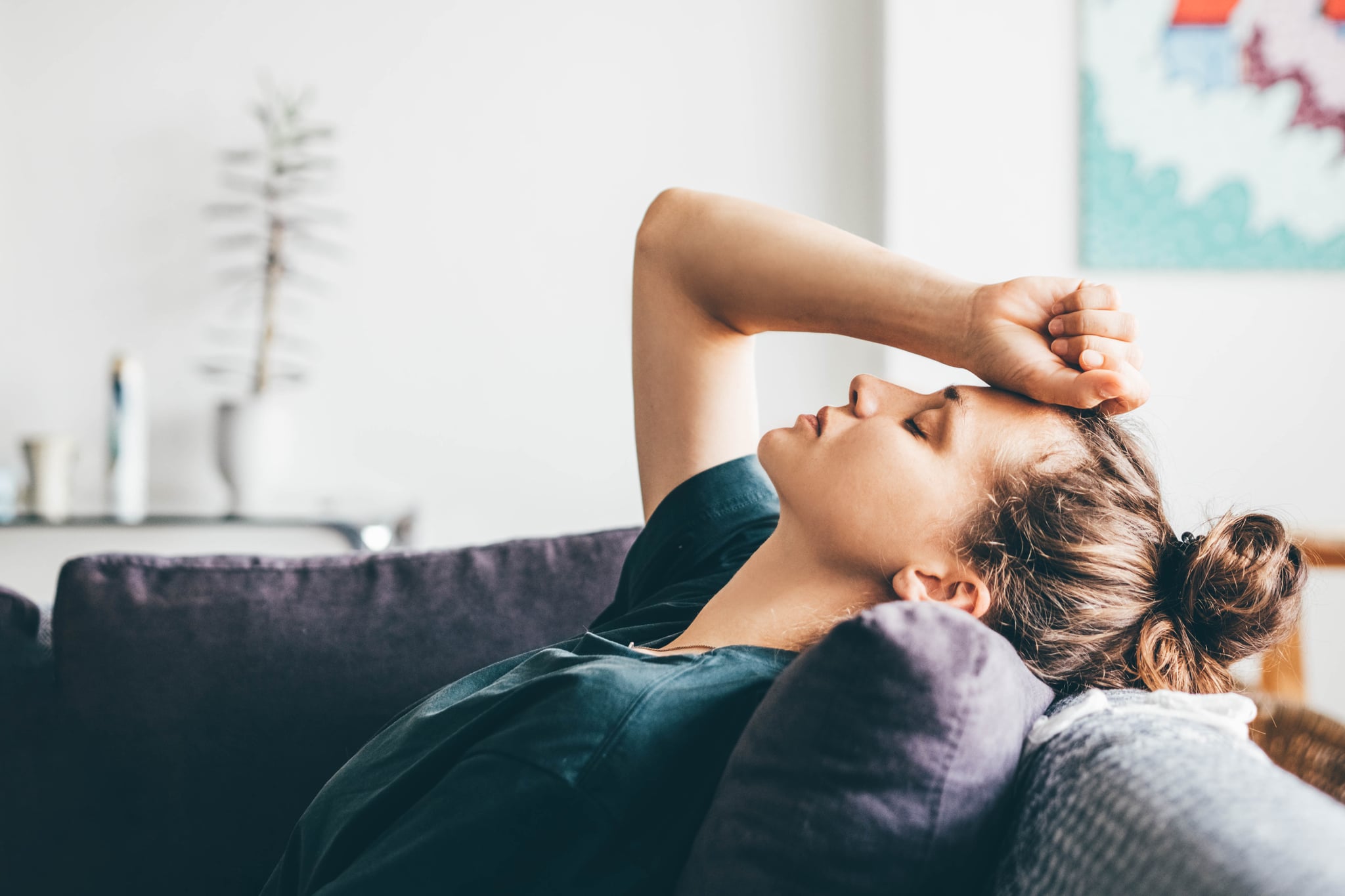 Woman laying down on couch from headache