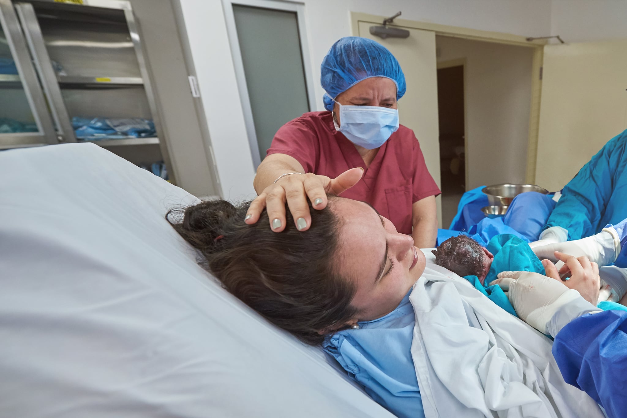 Young woman holding newborn baby in hospital bed