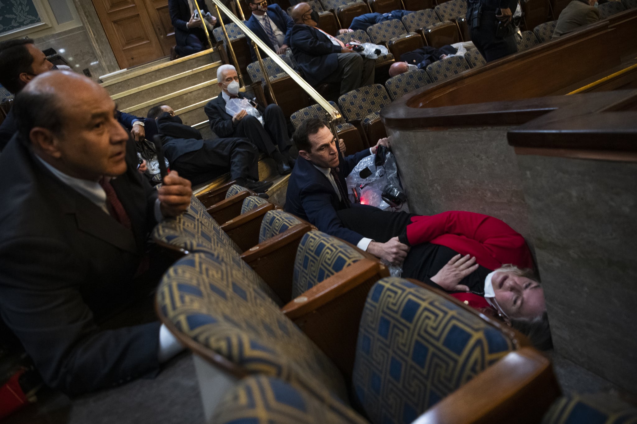 UNITED STATES - JANUARY 6: Rep. Jason Crow, D-Colo.,  comforts Rep. Susan Wild, D-Pa., while taking cover as protesters disrupt the joint session of Congress to certify the Electoral College vote on Wednesday, January 6, 2021. (Photo By Tom Williams/CQ-Roll Call, Inc via Getty Images)