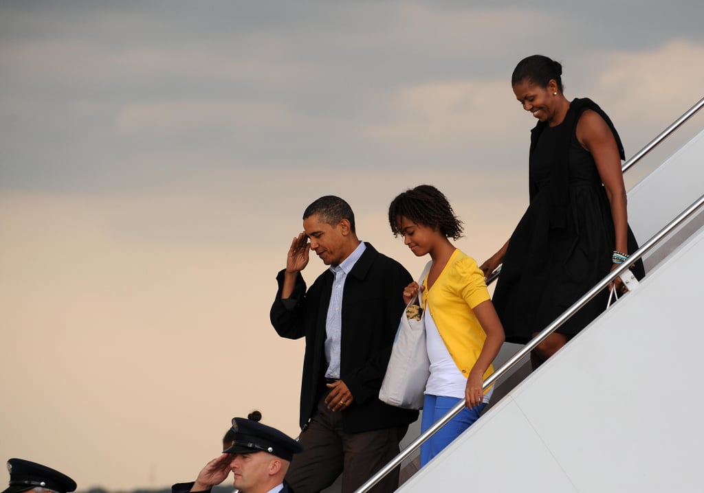 Michelle in a black tunic dress with bows returning from Martha's Vineyard.