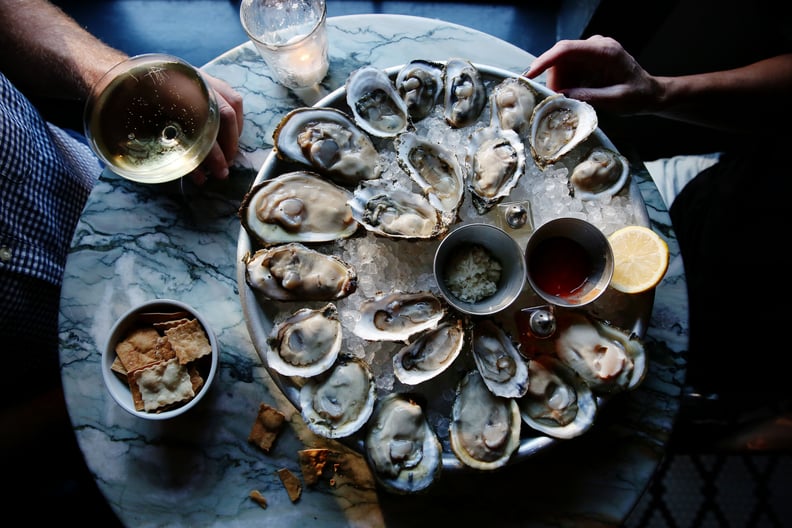 A couple enjoying raw oysters and champagne at a bar.