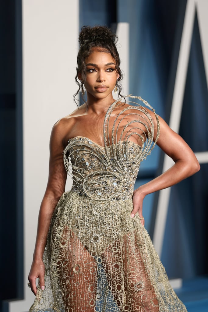 Lori Harvey arrived at Sunday's Vanity Fair Oscars party looking like a work of art. Perhaps the entrepreneur predicted the buzz surrounding her red carpet debut with boyfriend Michael B. Jordan, and she made sure to impress. Styled by Maeve Reilly, Harvey dressed in an embellished strapless gown with a sheer netted skirt. Adorned with intricate spiral pieces, the sparkly dress is by Tony Ward, the Lebanese-Italian fashion designer known for his innovative, sculptural creations. 
The skin-care brand founder pulled her hair back into a curly updo, drawing attention to her gold drop earrings and the rest of her stunning ensemble, which she paired with Jimmy Choo heels. Jordan looked dapper as usual, standing alongside Harvey in a sleek velvet black tuxedo and matching bow tie. 
Though the pair have worn some eye-catching styles on many date nights together, like on their 17-hour trip to Vegas or their lavish Valentine's Day date, Sunday's appearance marks their first red carpet as a couple. Jordan and Harvey have been dating since November 2020, making things Instagram official a few months later in January 2021.
While Harvey has been modeling since 2015, walking the runways of Michael Kors and Burberry shows in the past, she's lately become a style star to watch. In conjunction with her collaboration with Reilly, the founder of Skn by LH has been spotted in trendy ensembles and too many bold cutout dresses to count. Most recently, she wore a crisp menswear-inspired look — a white blazer with nothing underneath and matching trousers — to Kors's show at New York Fashion Week and a fun variety of nontraditional swimwear while on vacation in the Bahamas. 
Get a closer look at Harvey and Jordan's red carpet style ahead. 

    Related:

            
            
                                    
                            

            This Year&apos;s Oscars Red Carpet Might Be the Most Glamorous Yet