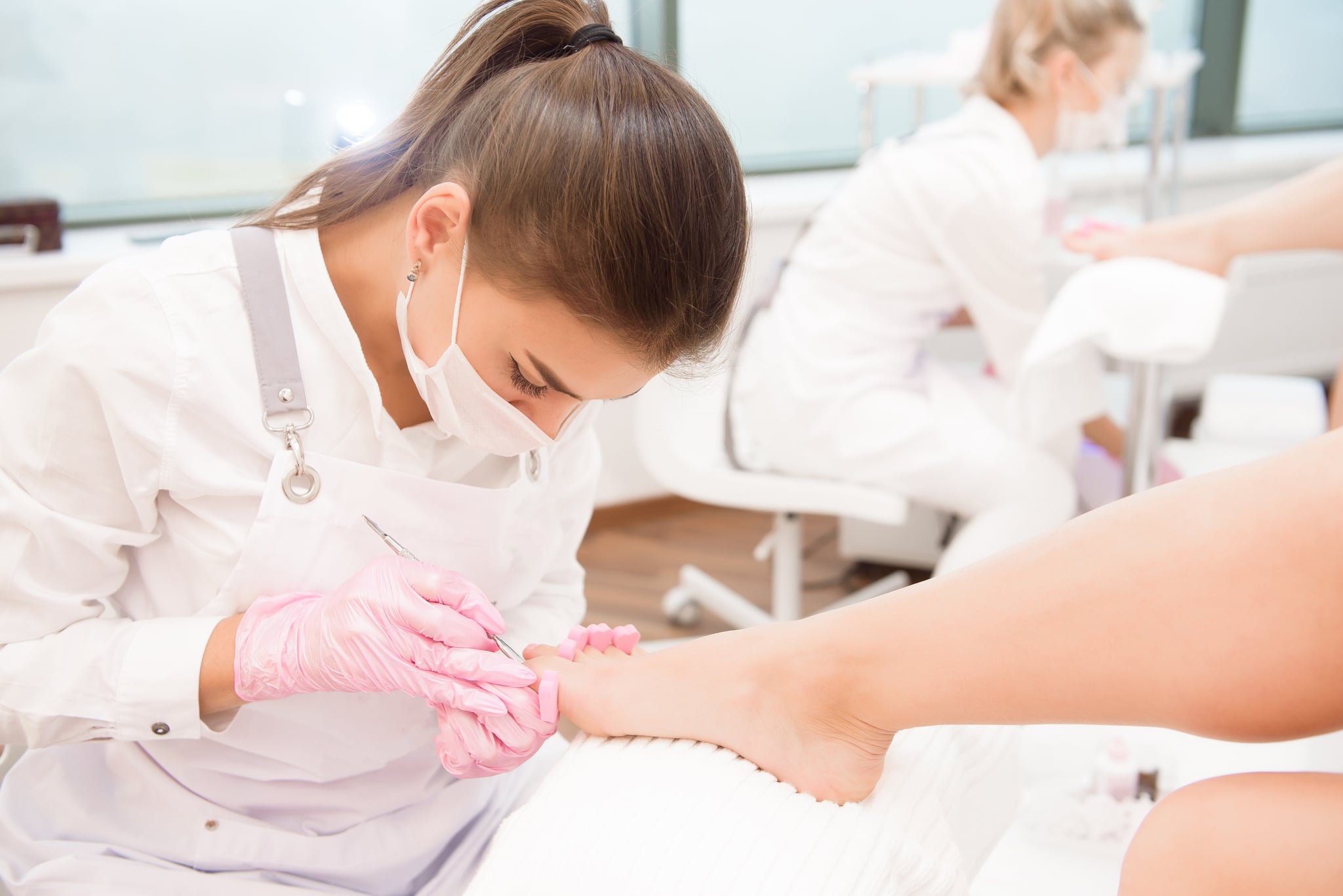 Foot treatment for two friends in SPA salon. Nail artist in beauty salon making pedicure for clients feet