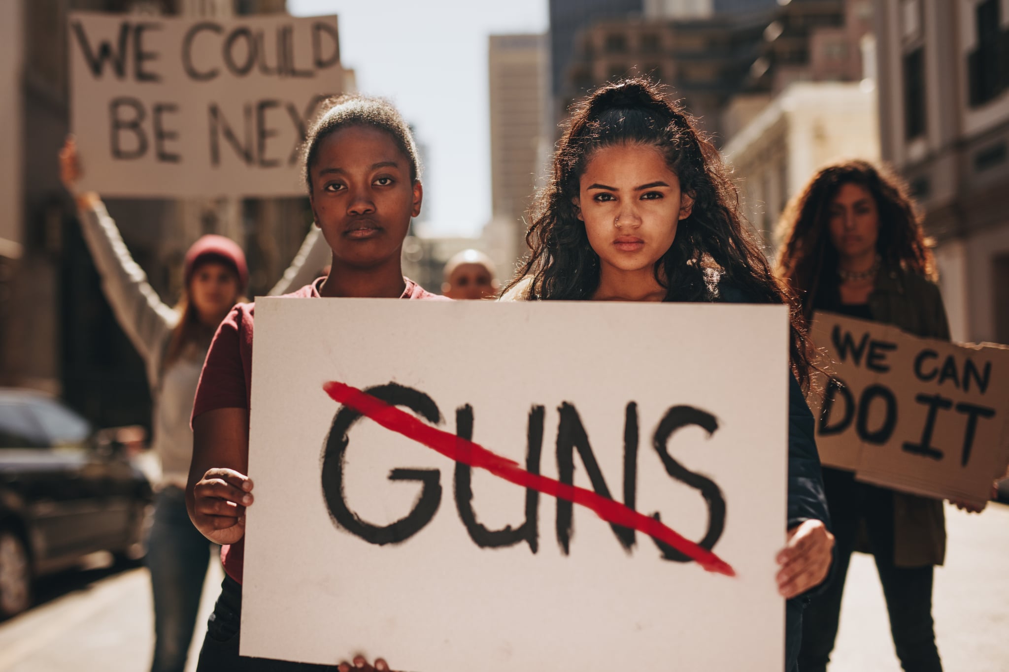 两个女孩拿着横幅和枪支删除线。女性持有表明没有枪的一次集会上说。