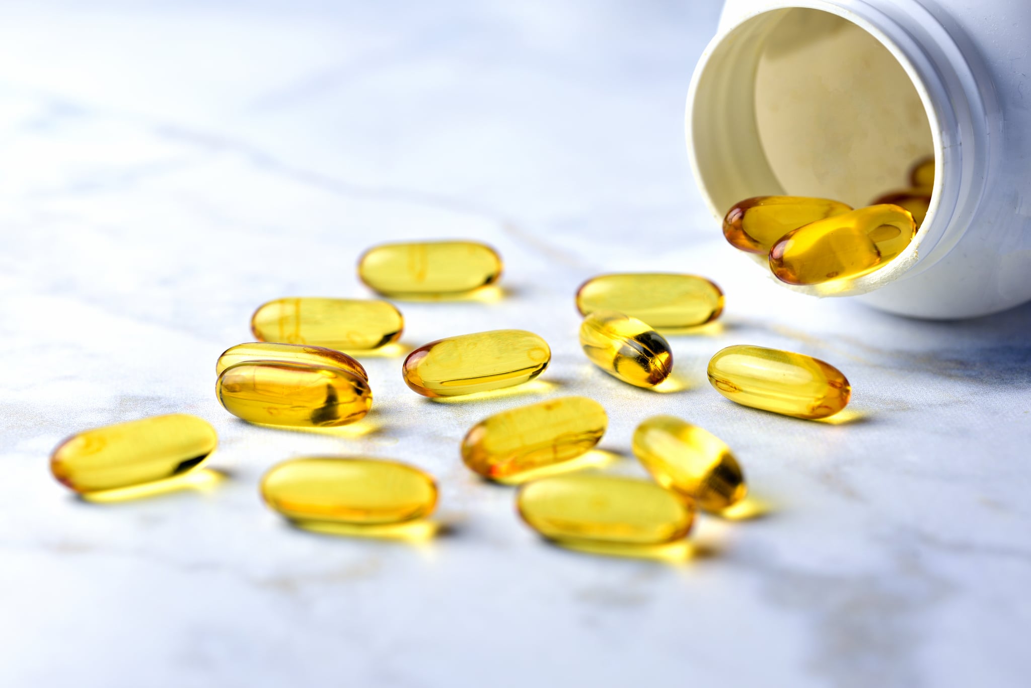 Bottle of yellow fish oil pills on table