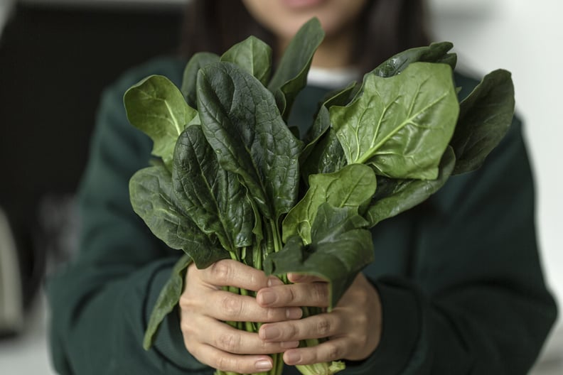Young woman holding spinach leafs salad.