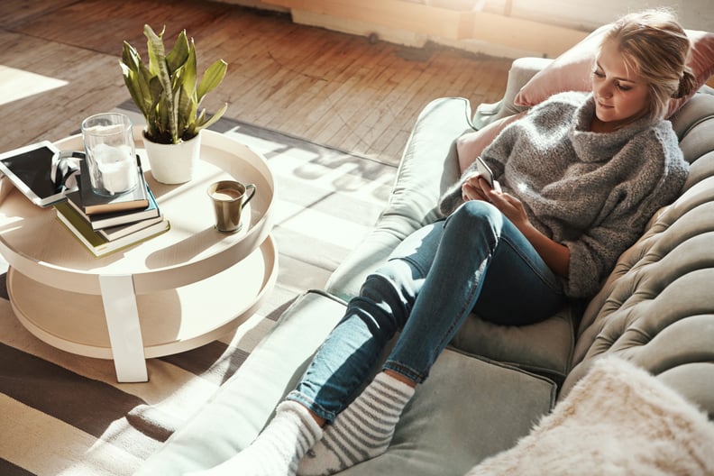 Shot of a young woman relaxing on the sofa at home and using a mobile phone