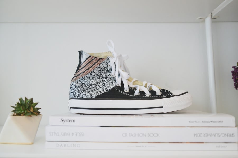 Homepolish designer and CEO Noa Santos wasted no opportunity to show off pieces from Leandra's vast fashion collection. A pair of Tibi x Converse high-tops are perched atop a pile of hip fashion reading, including Darling Magazine, System Magazine, and CR Fashion Book. A pop of green in the form of a succulent sits in a geometric vase and enlivens the bookshelf vignette. 
Photo by Claire Esparros via Style Me Pretty