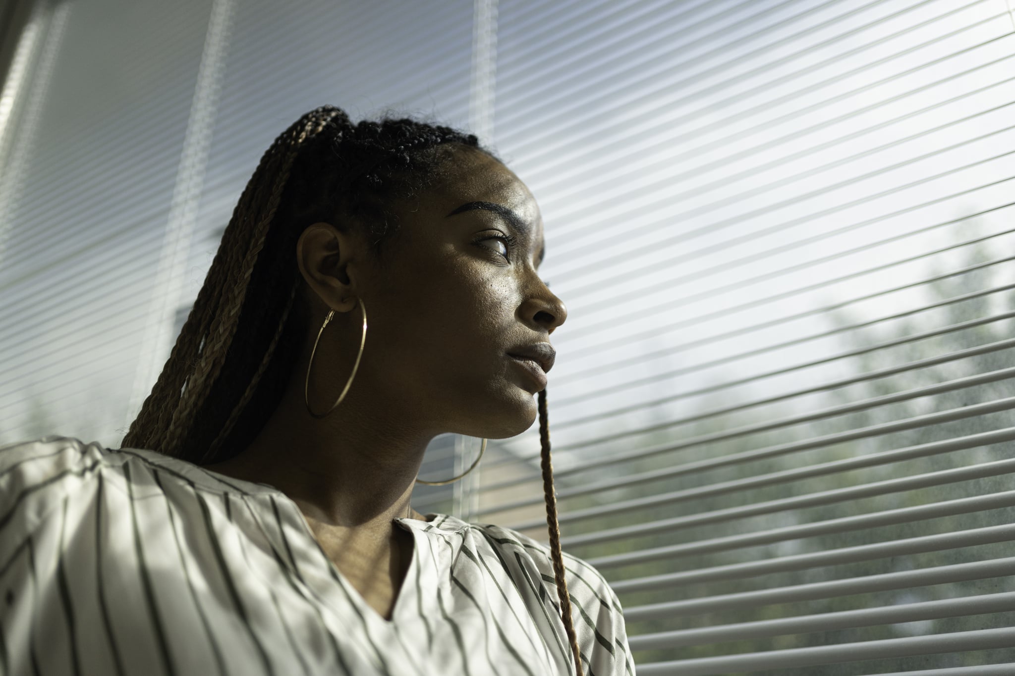 Pensive woman looking out a window at a sunny day.