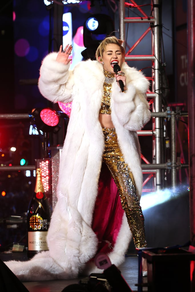 Miley Cyrus sparkled in a gold crop top and trousers (topped off with a gigantic white fur coat, of course) to perform in Times Square.