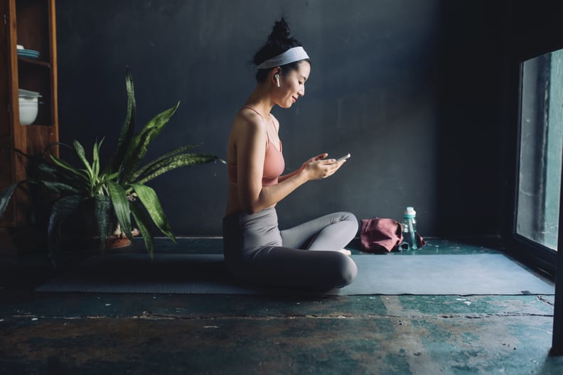 Young Asian woman with earphones sets up a music playlist before exercising.