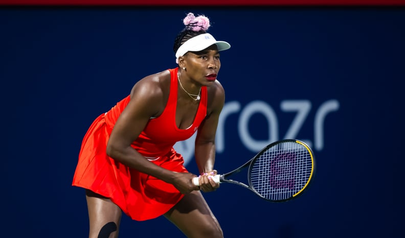Venus Williams in action wearing red tennis dress.