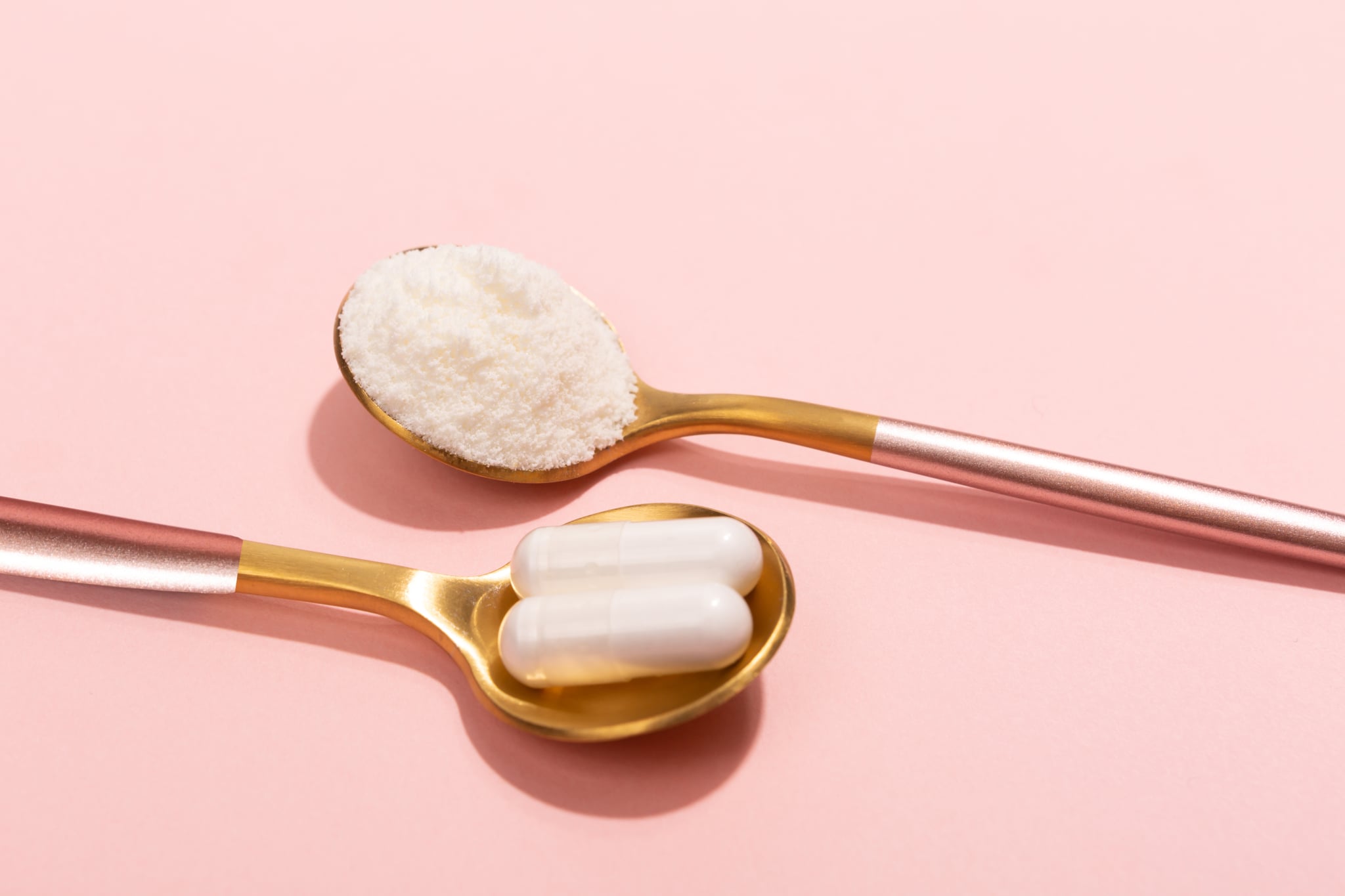 Collagen powder and pills on pink background. Extra protein intake. Natural beauty and health supplement for skin, bones, joints and gut. Plant or fish based. Flatlay, top view. Copy space for your text.