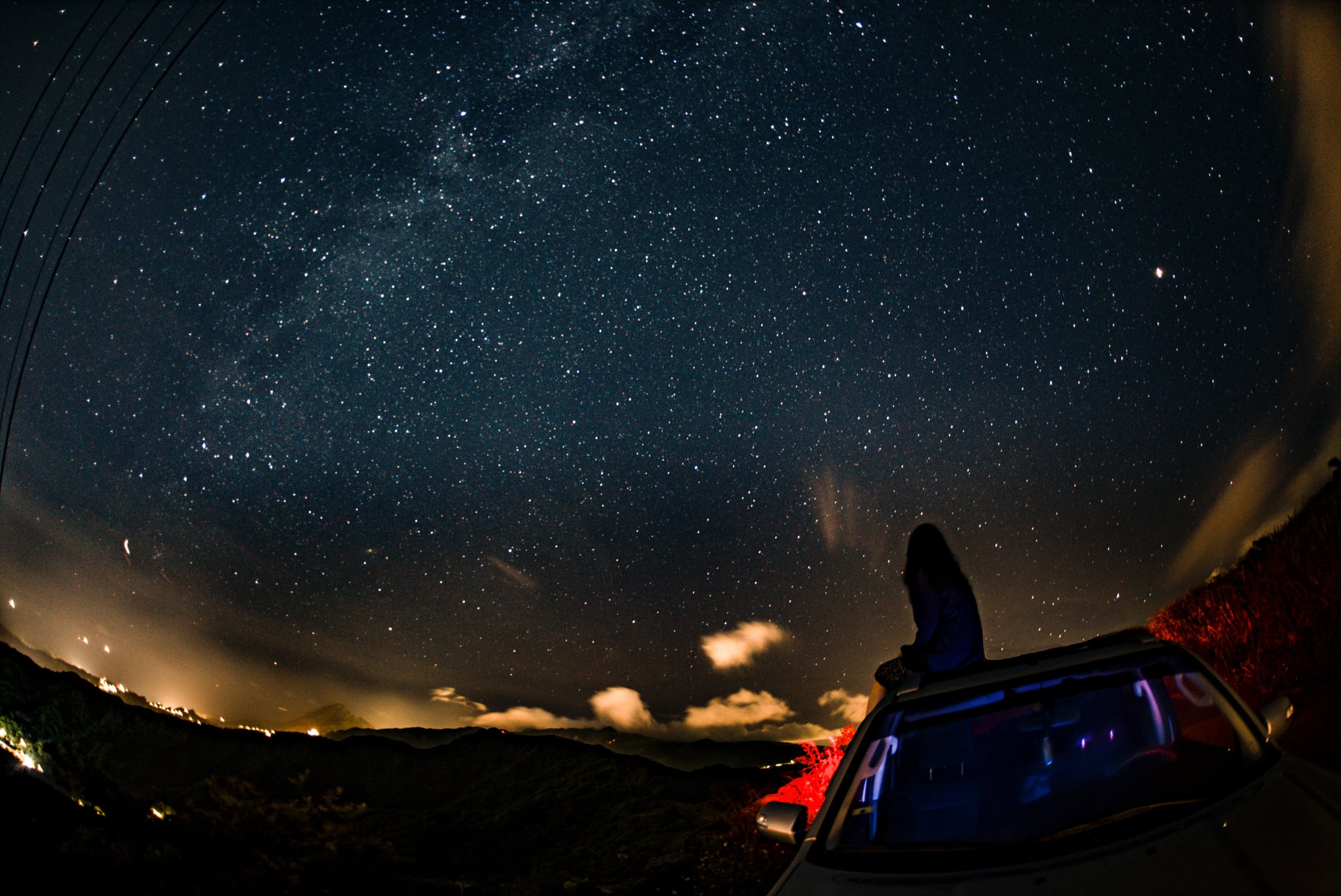 woman sitting on top of her car looking at a starry sky during planet retrogrades 2022