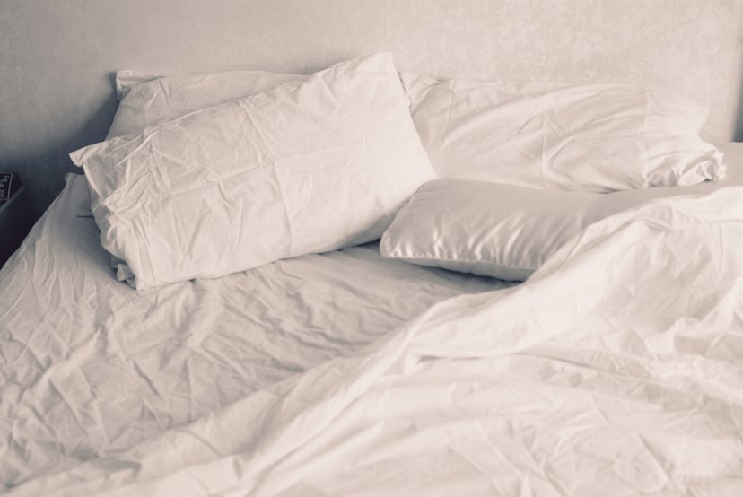 White linen of an unmade bed.