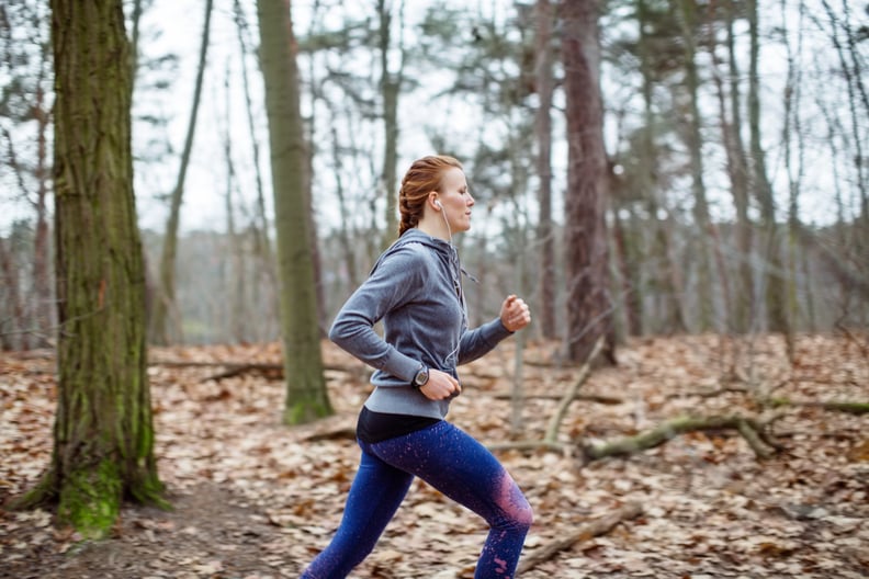 Side view of determined woman jogging in forest