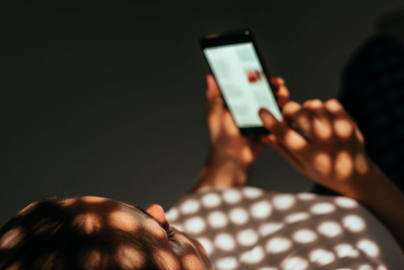 Woman using smart phone while lying on a bed at home