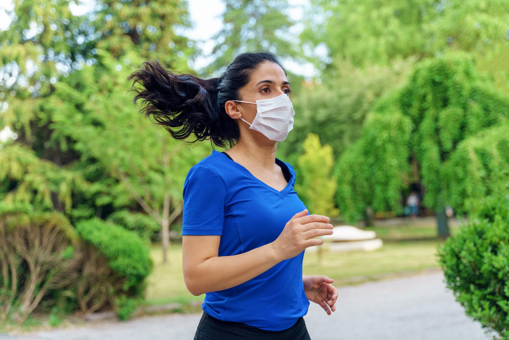 Woman running outdoors with a mask.