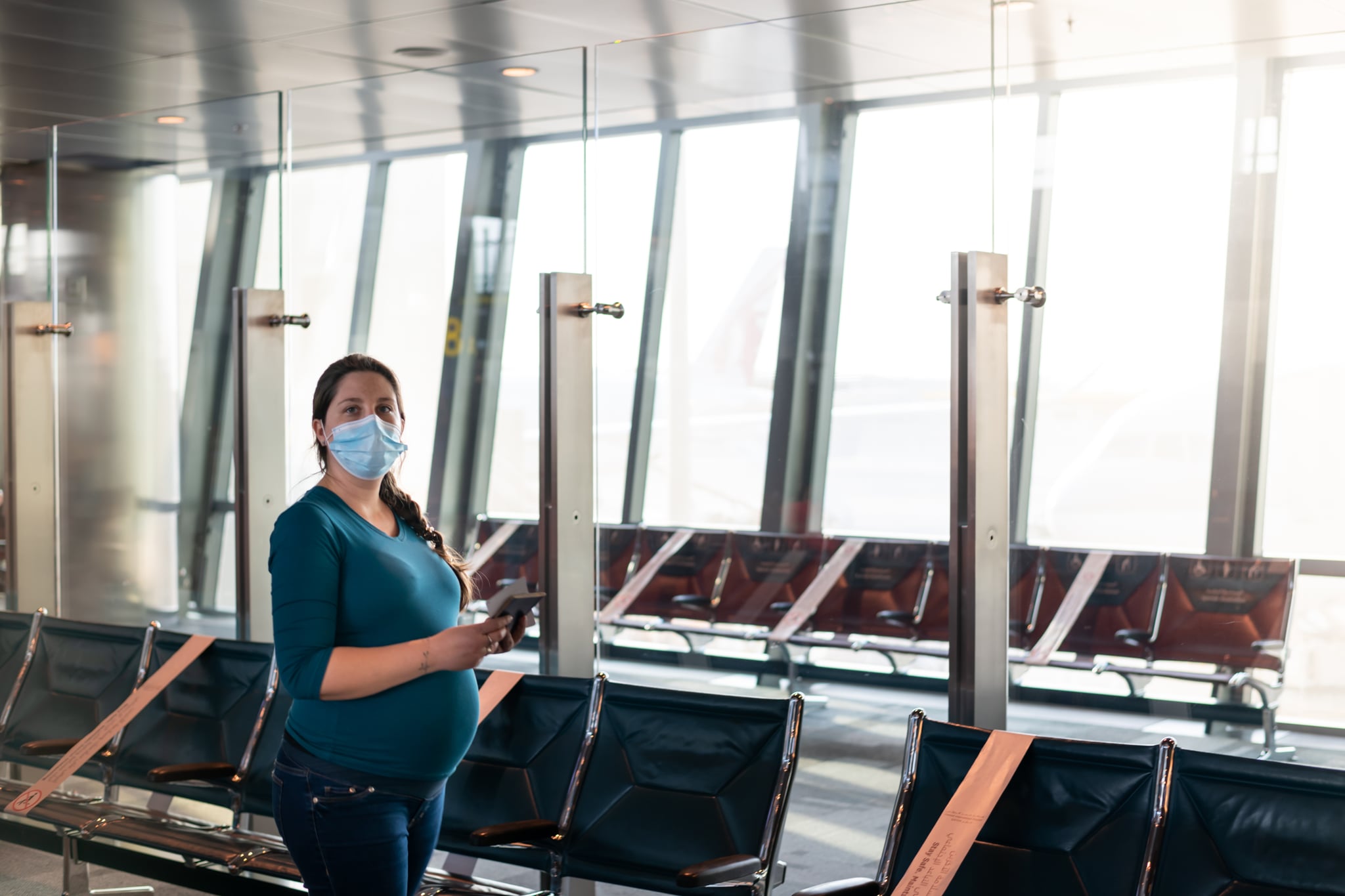 在冠状病毒大流行期间，孕妇戴着防护口罩等待航班。