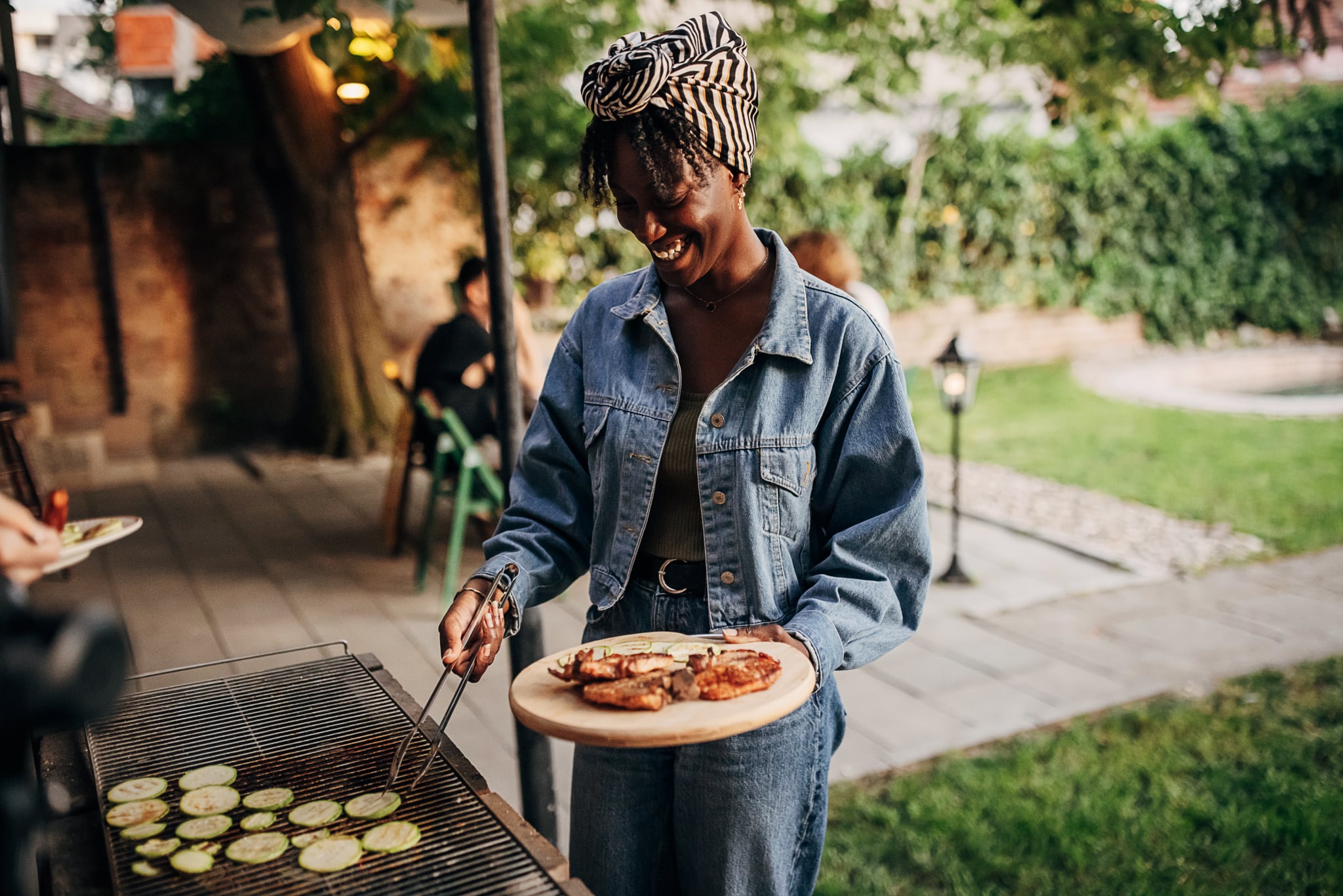 a woman grilling zucchini in the backyard