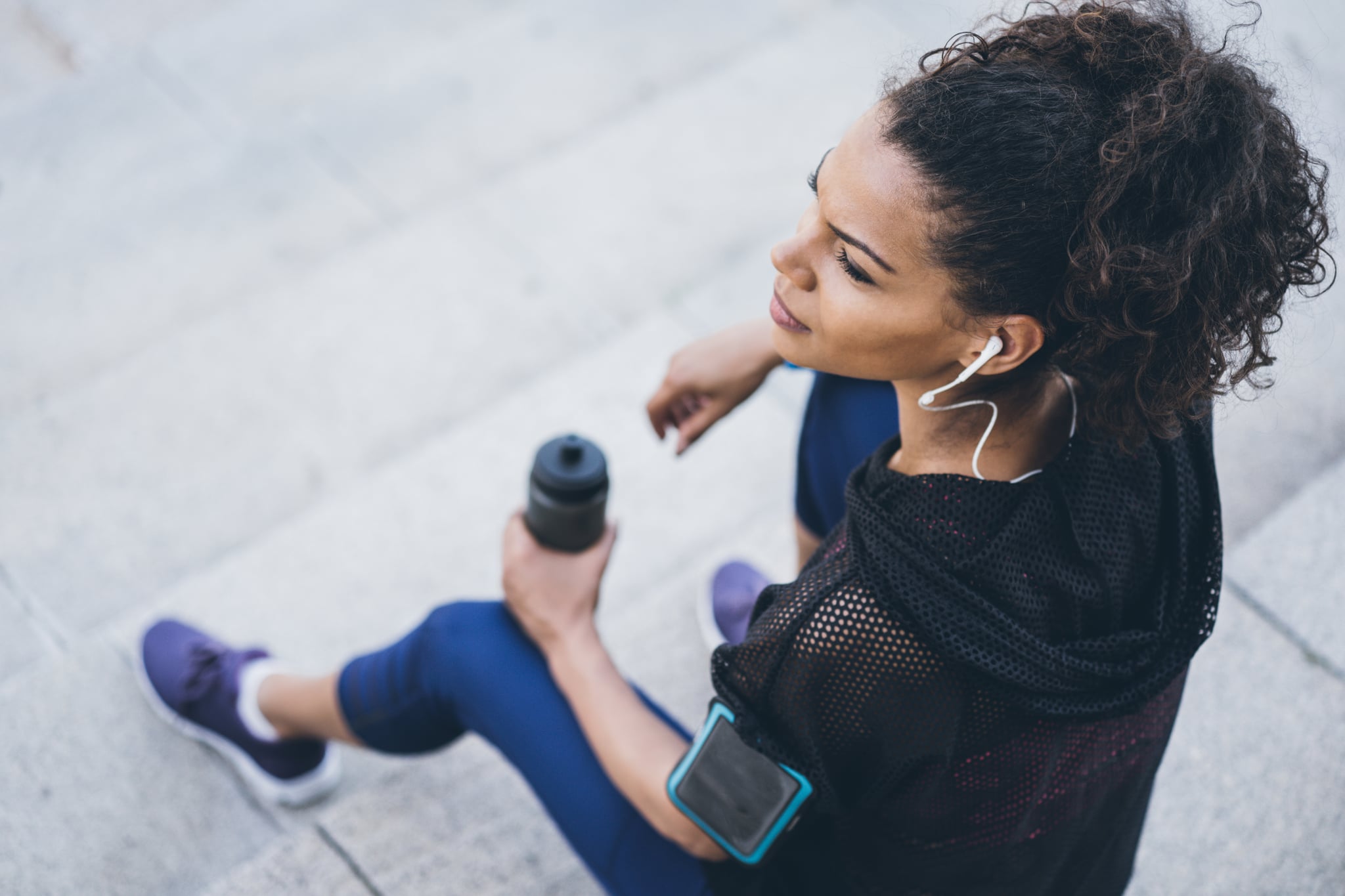 Sports woman resting after workout outdoors on the stairs